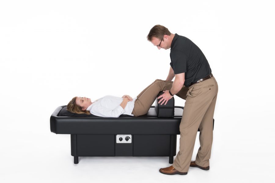 man adjust leg bolster on hydromassage table
